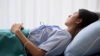 female patient in hospital bed . Sad young woman laying down in ward looking out of window . alone . worry - Powered by Adobe