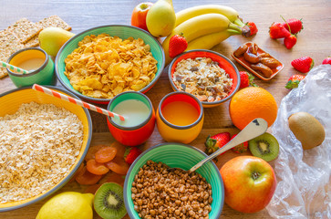 Varied healthy breakfast fruits, cereals, milk, dried plums, strawberries