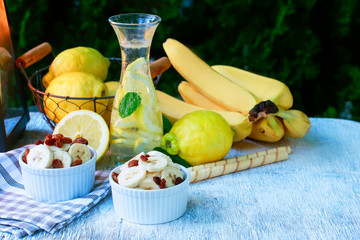 Lemonade in the bottle and fresh fruits in wire basket. Summer garden party