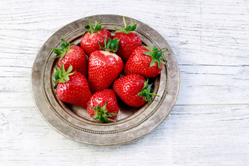 Bowl with strawberries on white wooden table.