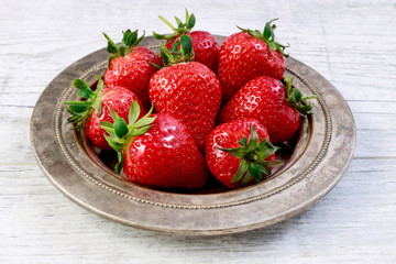 Bowl with strawberries on white wooden table.