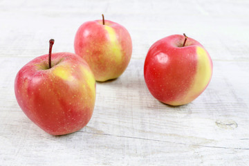 Red apples on white wooden table.