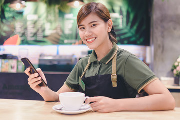 young woman sitting in a cafe at the table and use the phone - Image