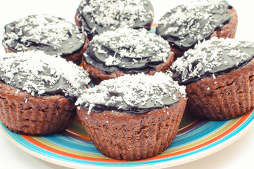 Fresh baked chocolate muffin with desiccated coconut on colorful plate. Delicious dessert