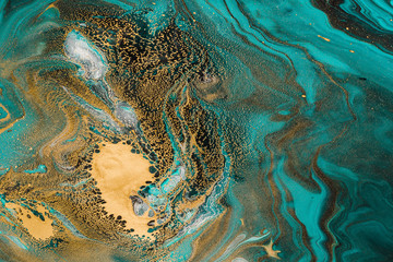 Acrylic Fluid Art. Turquoise waves and gold inclusion. Abstract stone background or texture