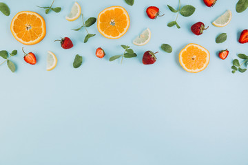Summer colorful flat lay. Pattern made of citrus fruits, leaves and strawberries on the blue wooden...