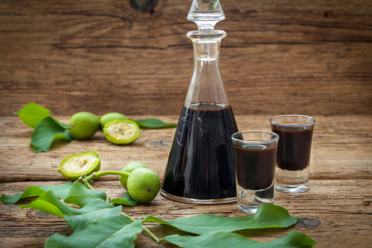 Bottle and two glasses with walnut liquor. Homemade wallnut liquer on rustic wooden background.