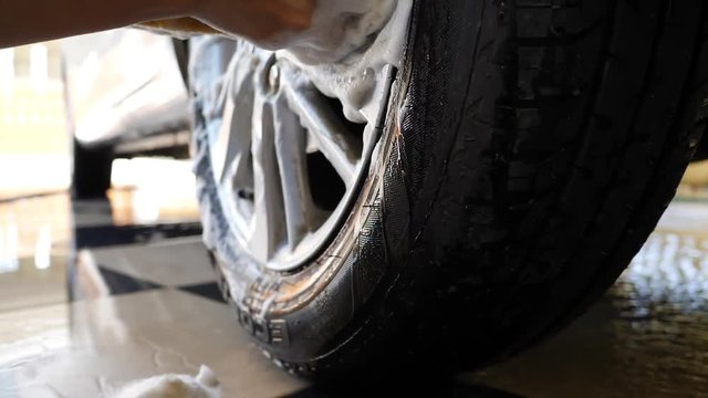 car wash slow motion, hand using sponge cleaning wheels
