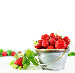 Juicy ripe tasty strawberries in  metal bucket on white wooden table.