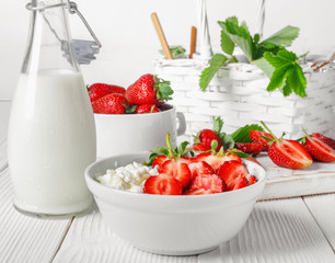 White bowl with fresh red ripe strawberries and natural cottage cheese