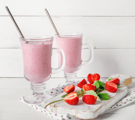Glass of fresh strawberry and yogurt smoothie on white wooden table