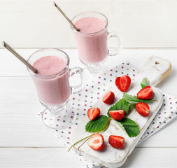 Glass of fresh strawberry and yogurt smoothie on white wooden table