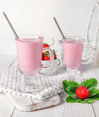 Glass of fresh strawberry and yogurt smoothie on white wooden table