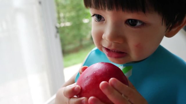 cute child eating bite red apple