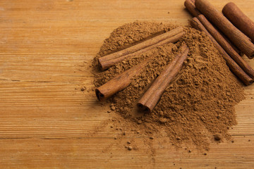 Cinnamon sticks and cocoa powder on wooden background