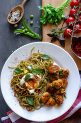 Spinach spaghetti with meatballs and egg. Green tasty pasta served with cherry tomatoes and basil