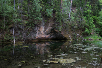City Cesis, Latvian Republic. Red rocks and water.  Green and overgrown forest. Jun 1. 2019 Travel photo.