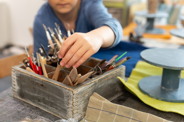Close up of schoolboy taking little palette knife for sculpting figures