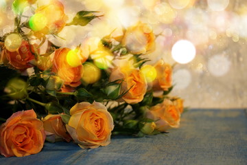   beautiful yellow roses with buds and green leaves lie on blue wooden boards on a shiny background