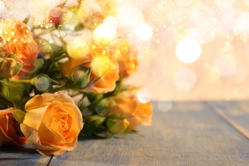   beautiful yellow roses with buds and green leaves lie on blue wooden boards on a shiny background