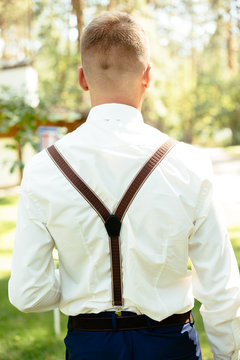 Groom back view  in white shirt with brown suspenders 