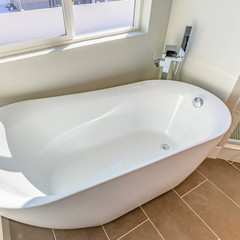 Square Interior of a bathroom with a smooth and glossy bathtub in th corner
