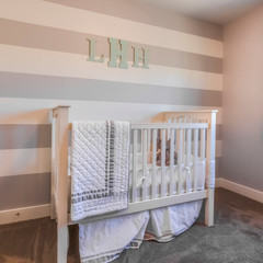 Square frame Interior of a nursery with white crib and monogram letters on the striped wall