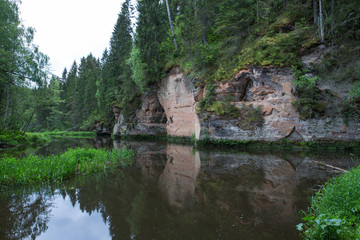 Fototapeta na wymiar City Straupe, Latvian Republic. Red rocks and river Brasla. Green and overgrown forest. Jun 1. 2019 Travel photo.