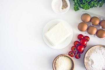 Ingredients for pizza, tomatoes, cheese, flour, eggs, yeast on a white background, flat lay, copy space