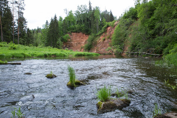 City Straupe, Latvian Republic. Red rocks and river Brasla. Green and overgrown forest. Jun 1. 2019 Travel photo.