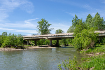 Fototapeta na wymiar Reinforced concrete road bridge over a picturesque river. Landscape.
