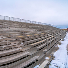 Square frame Row of tiered benches on a sports arena under a cloudy sky in winter