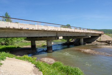 Fototapeta premium Reinforced concrete road bridge over a picturesque river. Close-up.