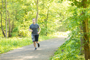 young man runs in a forest and makes fitness