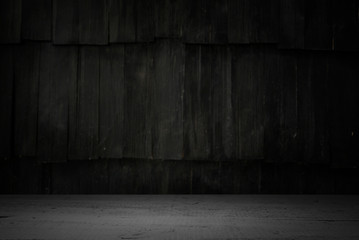 Old wood table with blurred concrete block wall in dark room background.