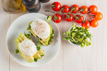 Avocado toast, cherry tomato and poached eggs on wooden background. Breakfast with vegetarian food, healthy diet concept.