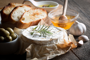 Camembert and brie cheese on wooden background with tomatoes, letuce and garlic. Italian food. Dairy products.