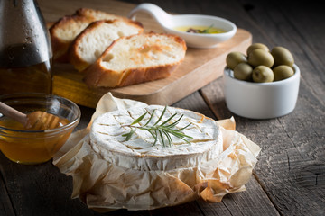 Camembert and brie cheese on wooden background with tomatoes, letuce and garlic. Italian food. Dairy products.