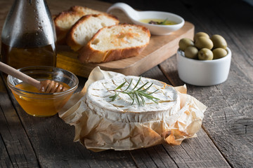 Camembert and brie cheese on wooden background with tomatoes, letuce and garlic. Italian food. Dairy products.