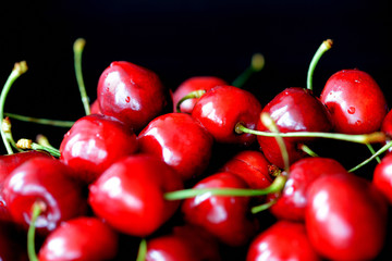 Ripe sweet cherry berries with water drops on a dark background close up
