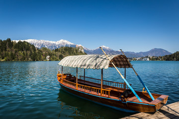 Naklejka na ściany i meble Boat floating on lake with snowy mountain view on springtime