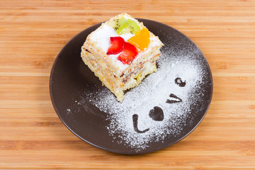 Piece of the layered sponge cake with fruits decoration