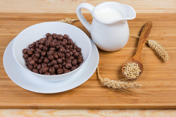 Breakfast cereal chocolate balls and milk among ears and grains