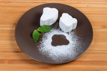 White marshmallow with mint leaves on the brown dish