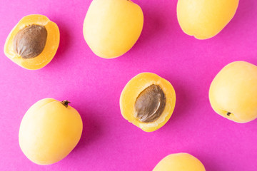 Apricots on a bright pink background. Summer ripe fruit. The concept of growing fruits, natural food rich in vitamins. Minimalism, flat lay, top view, design.