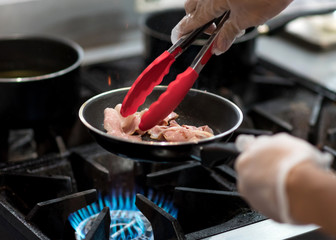 chef cooking in the kitchen, fresh fried bacon in a pan