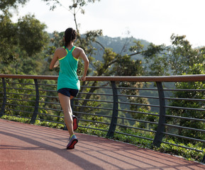 Runner athlete running on spring forest trail. woman fitness jogging workout wellness concept.