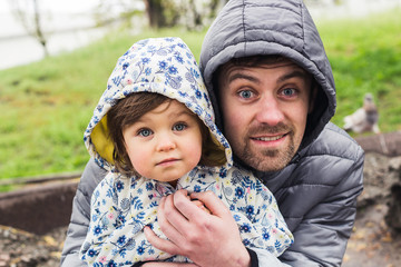 Father and daughter wearing coats and hoods spend quality time outdoors. Family and fatherhood concept