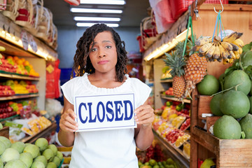 Obraz premium Sad Black young woman closing her grocery store with no customers inside
