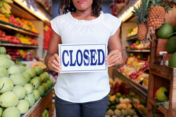 Closed sign in hands of female organic grocery store owner